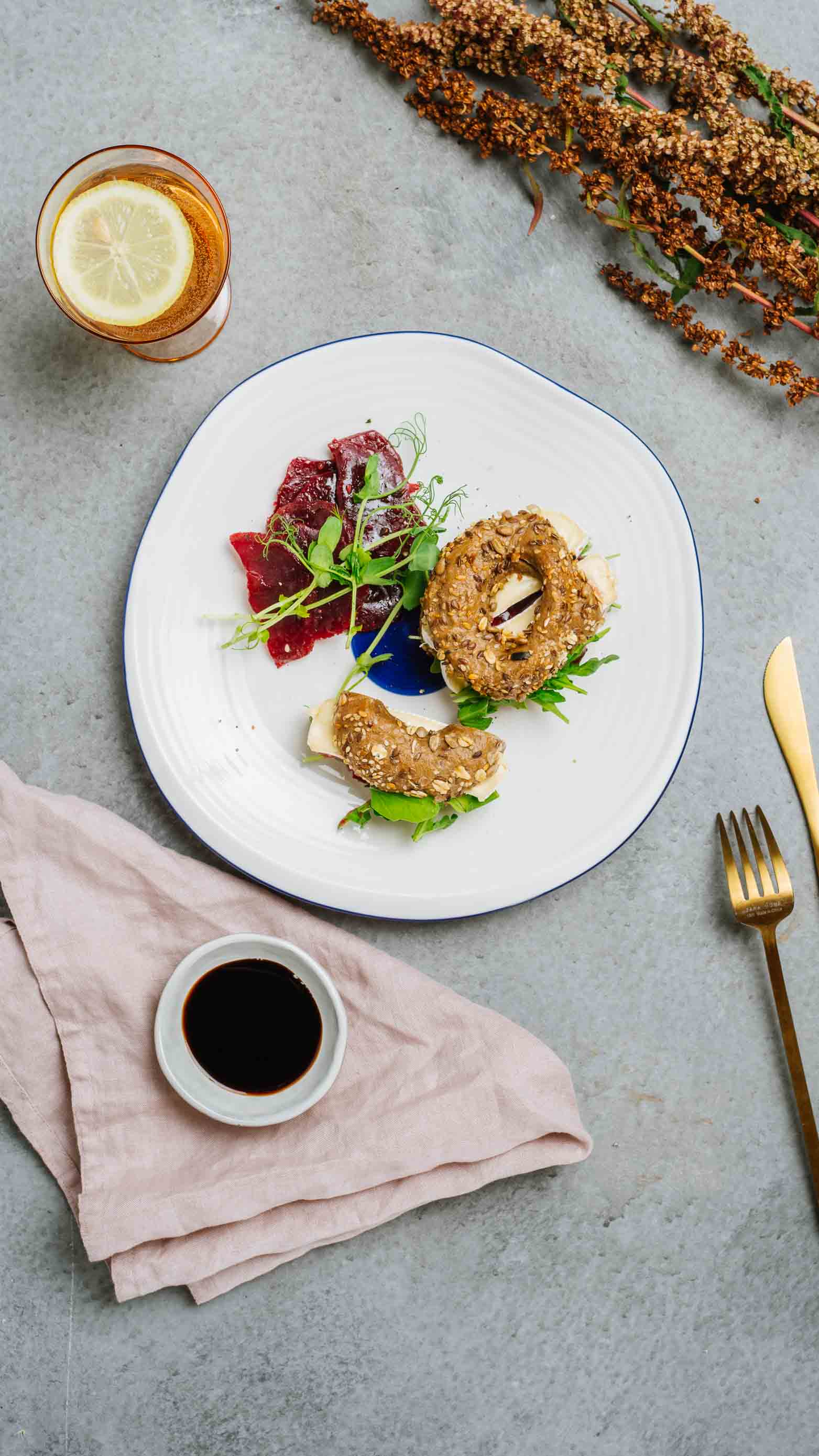 Bajgiel z ziarnami z konfiturą żurawinową, serem camembert i rukolą, carpaccio z buraka, krem balsamiczny